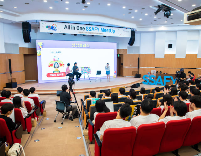 대규모 강연장에서 열린 ‘All in One SSAFY MeetUp’ 행사에서 청년 소프트웨어 아카데미 교육생들이 강연을 듣고 있습니다.